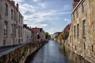 Canal amidst buildings in city against sky