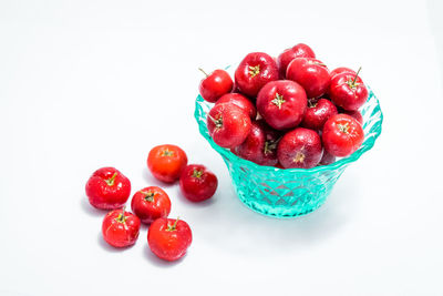 Close-up of cherries in bowl against white background