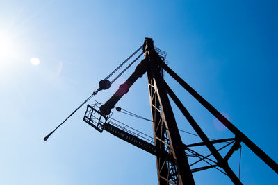 Low angle view of crane against clear blue sky