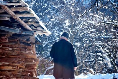 Rear view of man standing against bare trees during winter