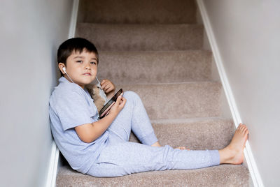 Portrait of boy sitting on staircase at home