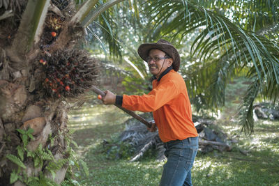 Man wearing hat working by tree at farm