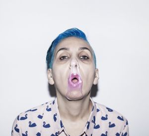 Portrait of mature woman with chewing gum standing against white background