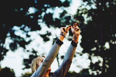 Woman with arms raised against trees