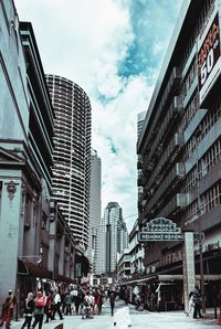 People on city street amidst buildings against sky