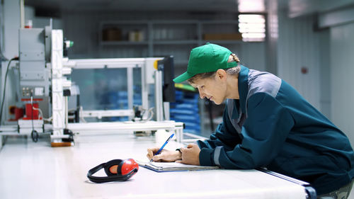 Elderly woman, employee, worker at an enterprise, factory, fills up a service journal, record book