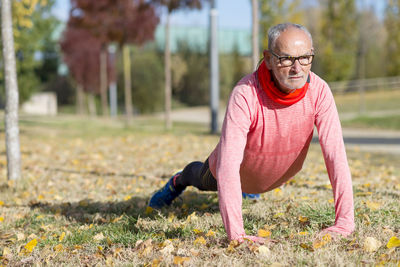 Senior man doing push-ups on grassy field at park