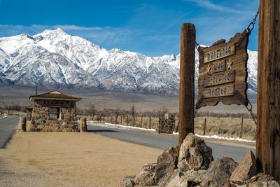 Manzanar entrance sign and sentry  station with snowcapped mountains against sky