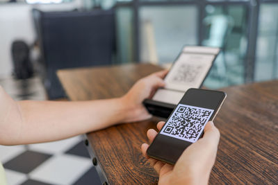 Midsection of person using mobile phone on table