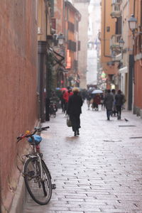 Rear view of people walking on street amidst buildings in bologna