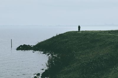 Silhouette of woman standing by sea against sky