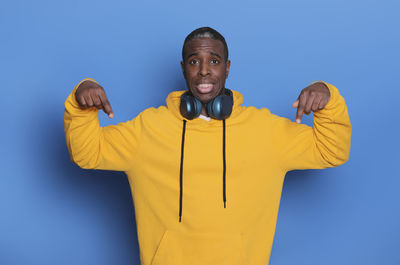 Portrait of man gesturing while standing against blue background