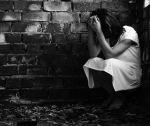 Full length of woman crouching in corner at abandoned house