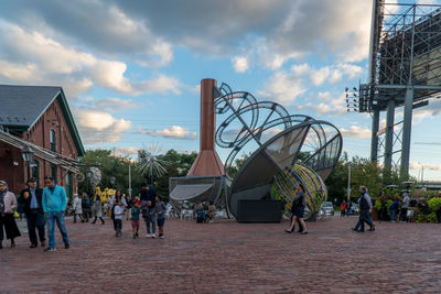 People at amusement park in city against sky