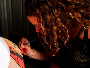 Woman painting on pregnant friend belly