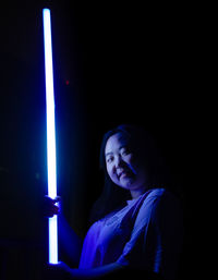 Portrait of young man standing against black background