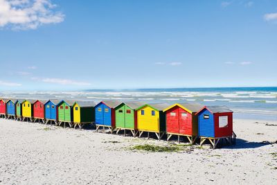 Multi colored beach huts on shore against sky