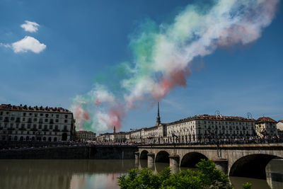 Bridge over river against sky in city