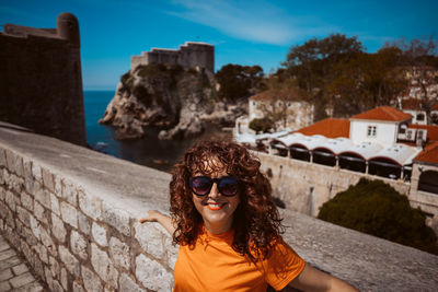 Portrait of woman wearing sunglasses while standing against mountain