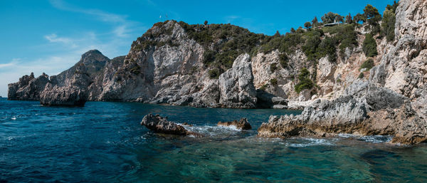 Scenic view of sea by rock formation against sky