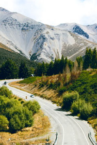 Road amidst trees and mountains against sky