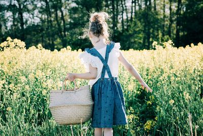 Woman standing by flowering plants on field