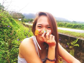 Portrait of beautiful young woman holding sunglasses on field