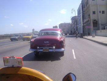 Cars on road against sky in city