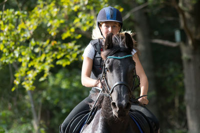 Jockey riding horse against trees in forest during training