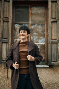 Portrait of young woman standing against wall