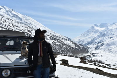 Woman standing on snowcapped mountain against sky