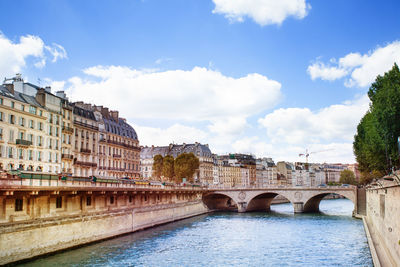 Bridge over river in city against sky