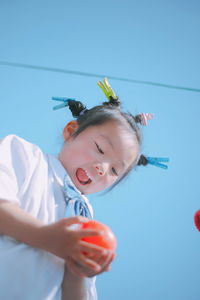 Low angle view of cute girl holding toy while standing against sky