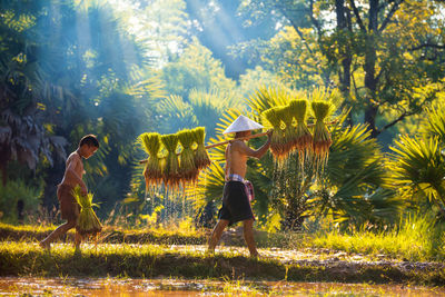 Side view of people on field against trees