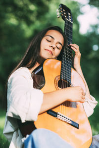 An attractive girl with a guitar in the park. the concept of creative hobbies and professionals. 