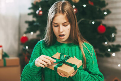 A beautiful girl with a surprised face opens a kraft paper gift 