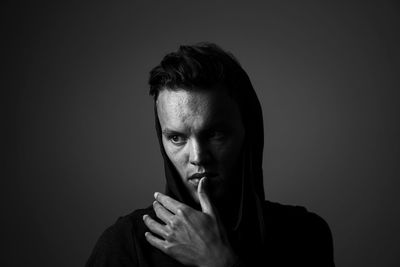 Portrait of young man looking away against black background