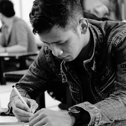 Man writing in book at classroom