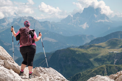 Rear view of man standing on mountain against sky