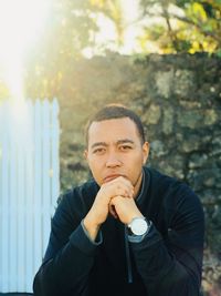 Portrait of young man contemplating while sitting against stone wall