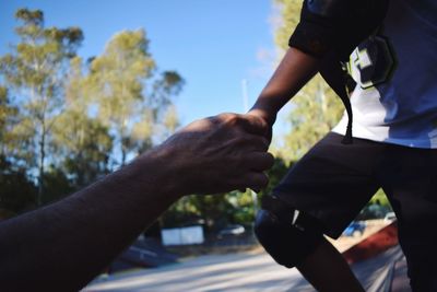 Close-up of hands against sky in city