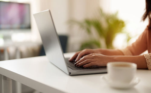 Midsection of woman using laptop on table