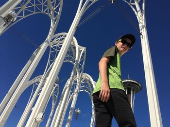 Low angle portrait of boy metal structure against clear blue sky at pacific science center