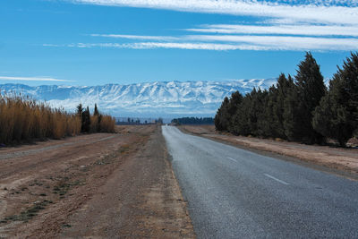 Road by mountains against sky during winter