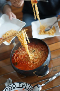 Cropped image of people serving noodles in plate