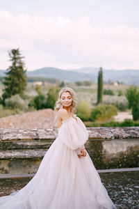 Young woman with arms outstretched standing against sky