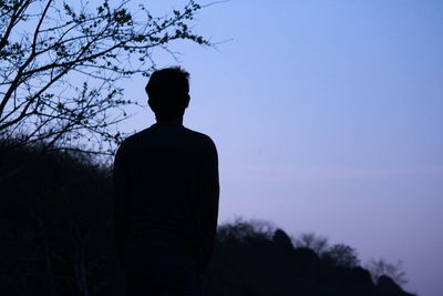 Rear view of man standing against clear sky