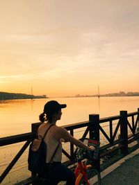 Rear view of woman looking at sea against sky during sunset