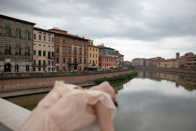 Woman leaning on railing against canal in city