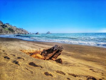 Scenic view of beach against clear blue sky